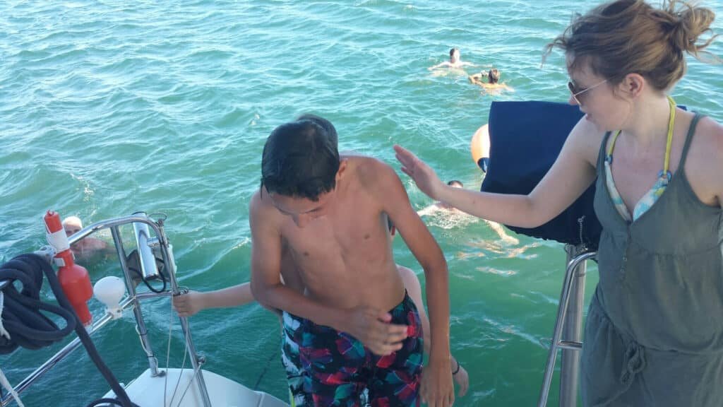 Jovem a sair da água e a entrar no catamaran