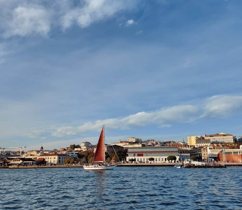 Cais do Sodré visto desde o rio Tejo e um veleiro de velas vermelhas