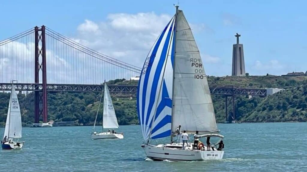 O "Sail la Vie" navegando nas águas do rio tejo, com vista para a Ponte 25 de Abril e o Cristo Rei