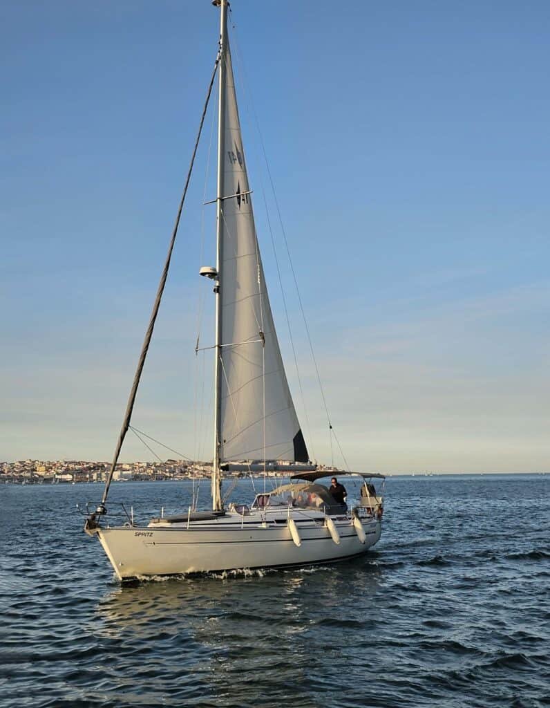 Magnífico veleiro a navegar em direção ao pôr do sol, desfrutando de vistas deslumbrantes sobre as margens do rio tejo