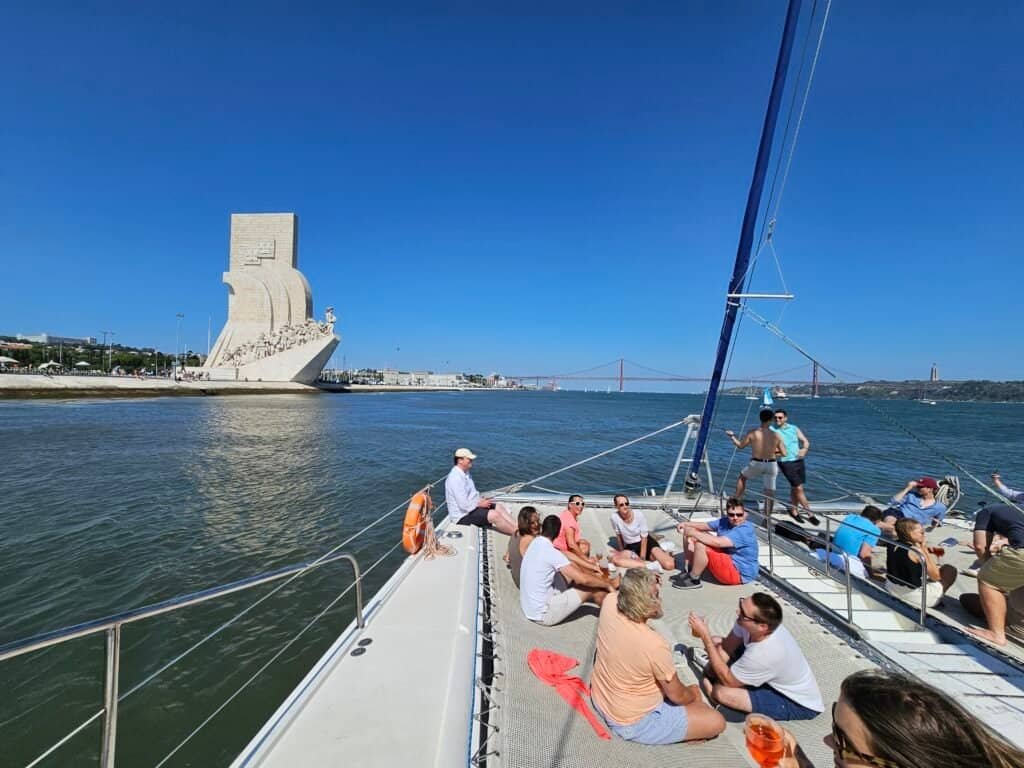 Convidados da Berg Lund & Company, durante um passeio no rio Tejo, com o Padrão dos Descobrimentos e a Ponte 25 de Abril no fundo.