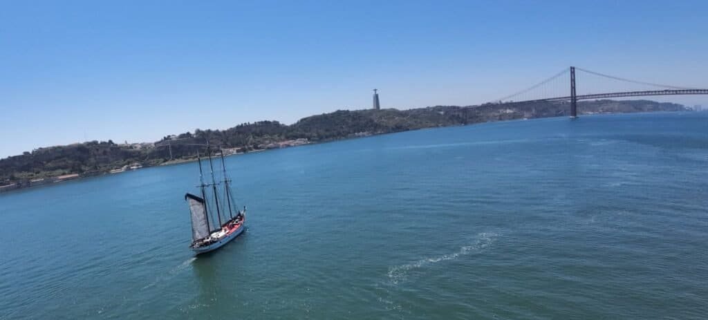 Veleiro a navegar pelo rio Tejo, em direção à Ponte 25 de abril e ao Cristo Rei